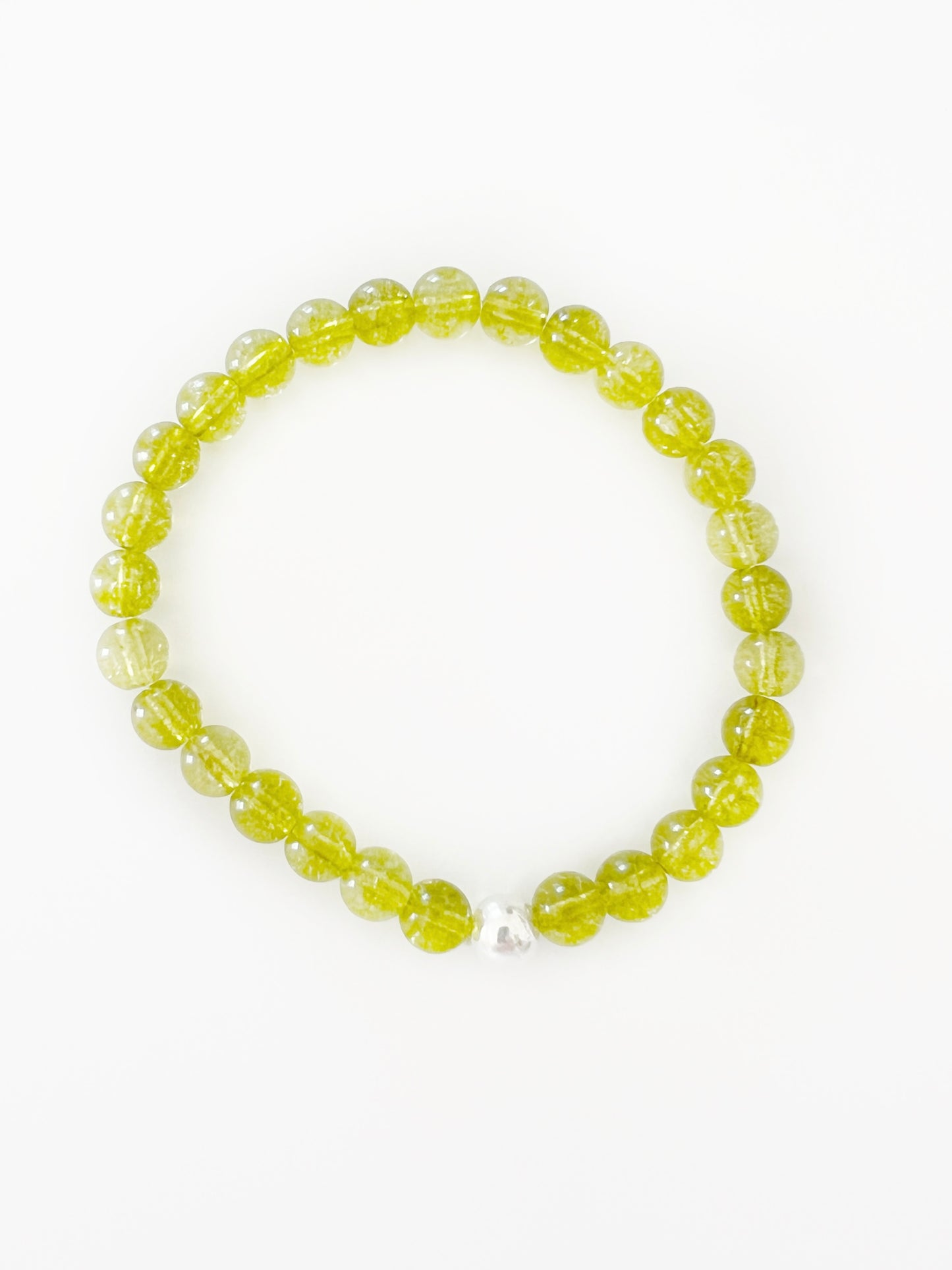 a translucent green stretch bracelet with one silver bead.