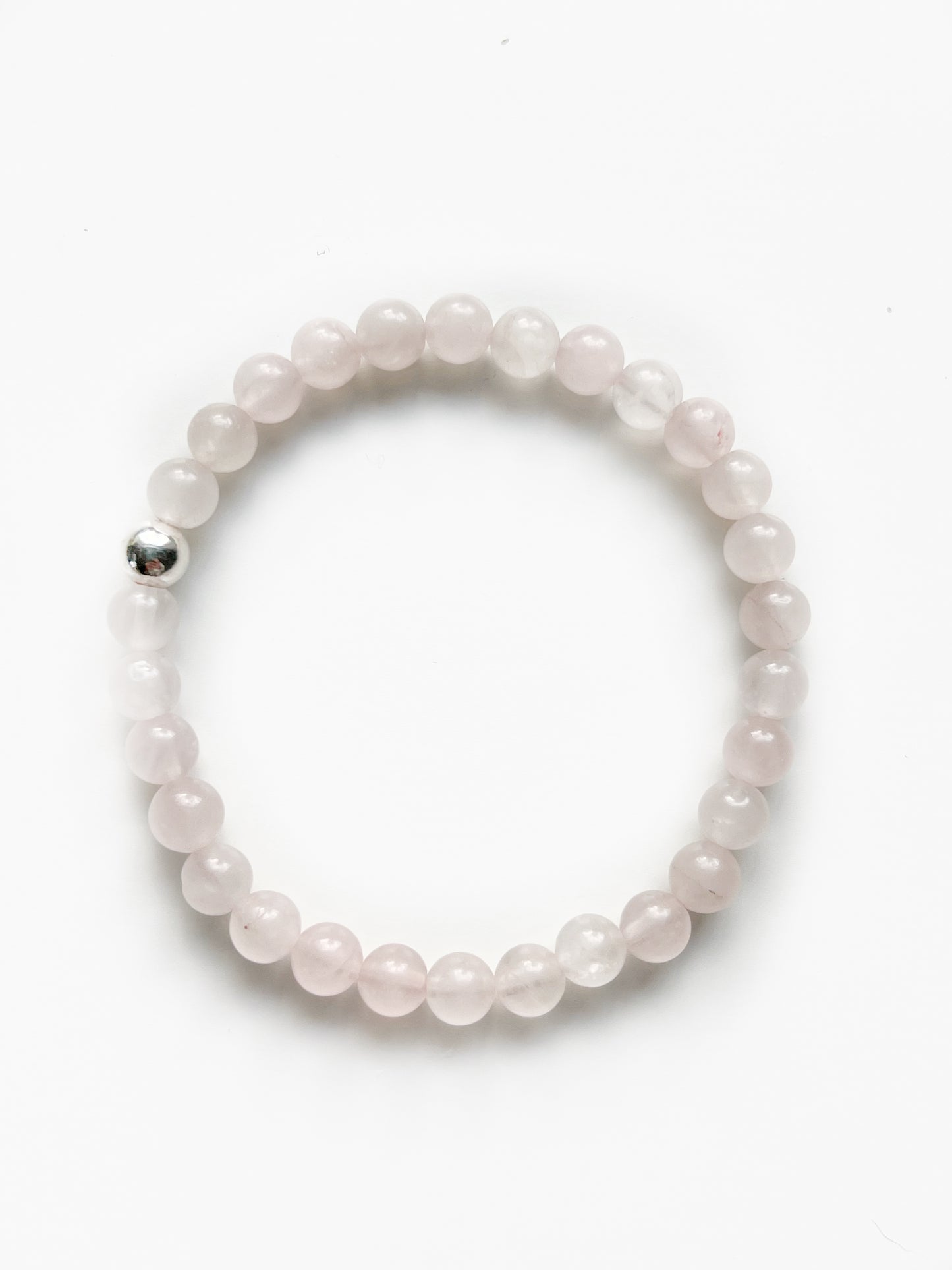 Rose Quartz stretch bracelet with one silver bead on a white background.