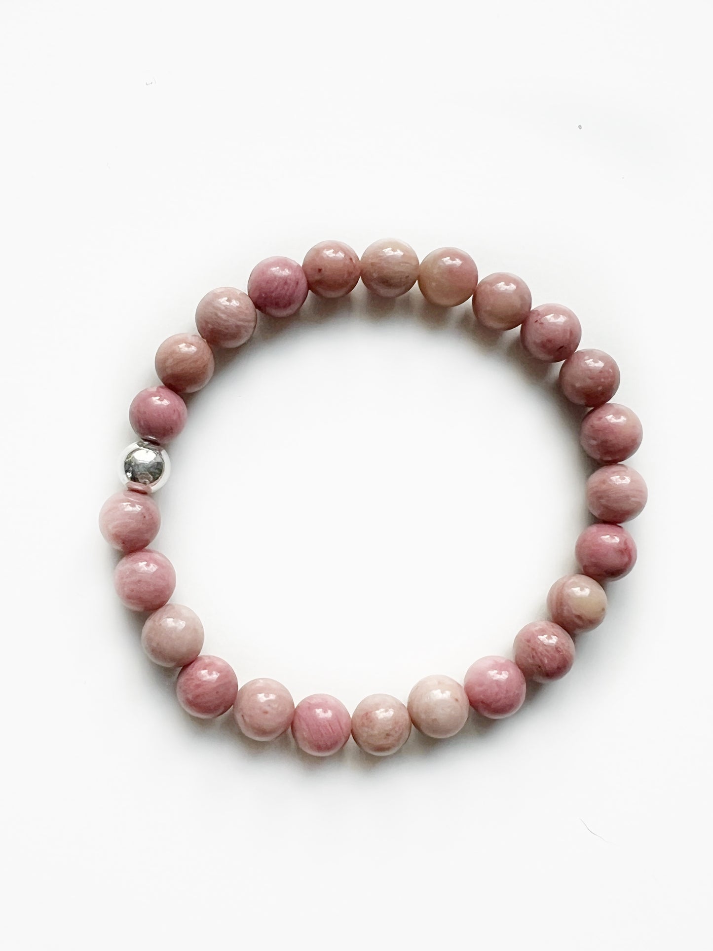 Rhodonite stretch bracelet, opaque baby pink, with one silver bead on a white background