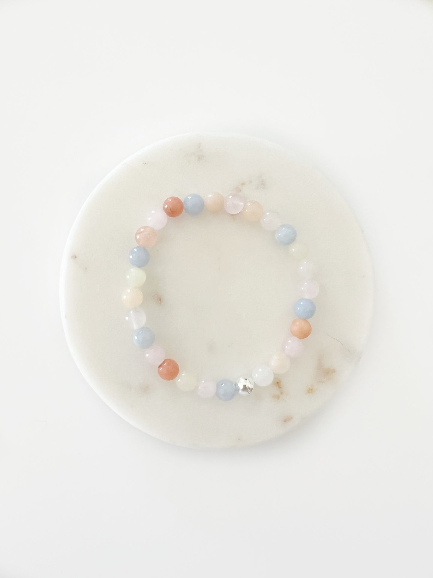 Morganite stretch bracelet with one silver bead on a marbled small circle tray