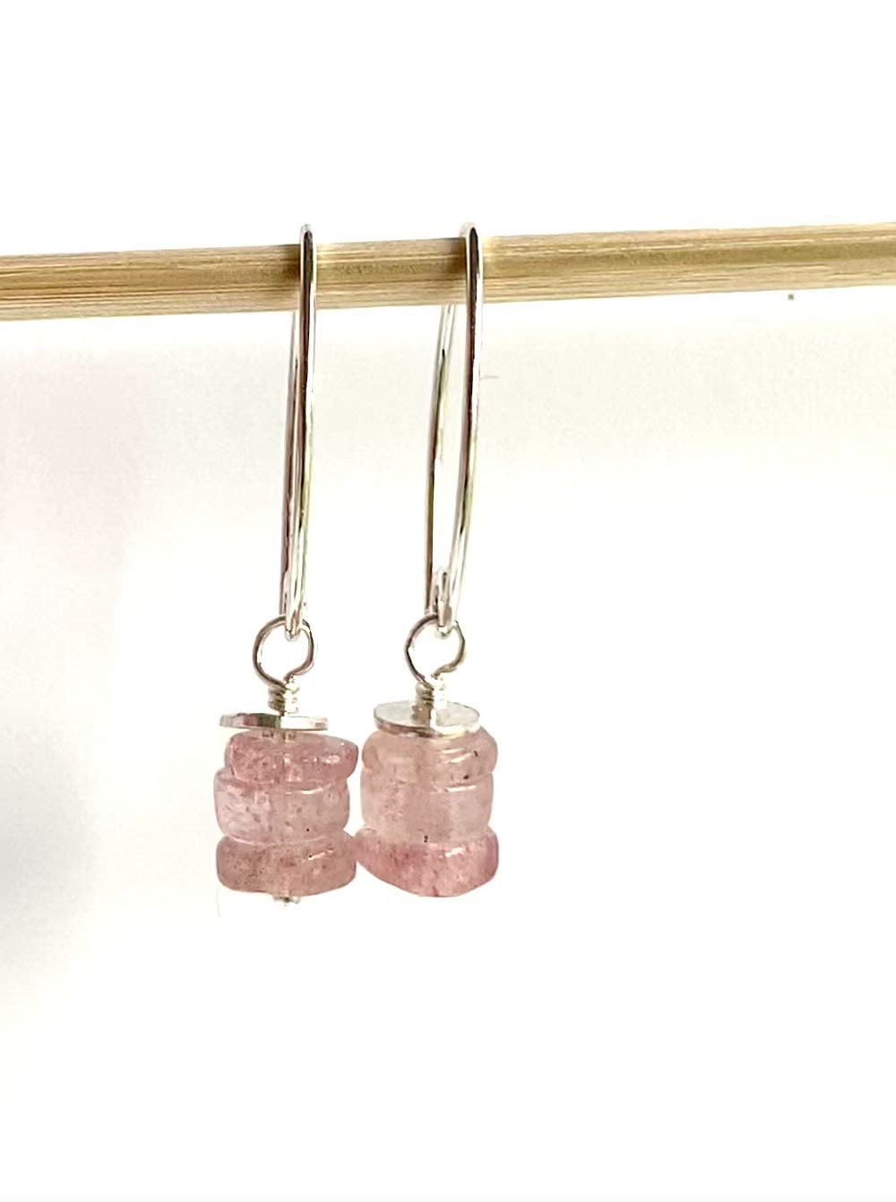 Load and play video in Gallery viewer, video of strawberry quartz earrings dangling from a small dowel