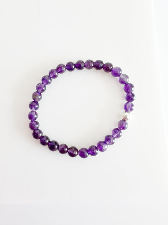 amethyst stretch bracelet. deep purple round beads with one silver bead