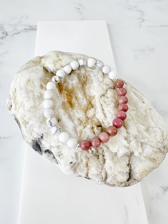 Simple and fun Howlite and Rhodonite stretch bracelet with one Sterling Silver bead on a brownish rock.