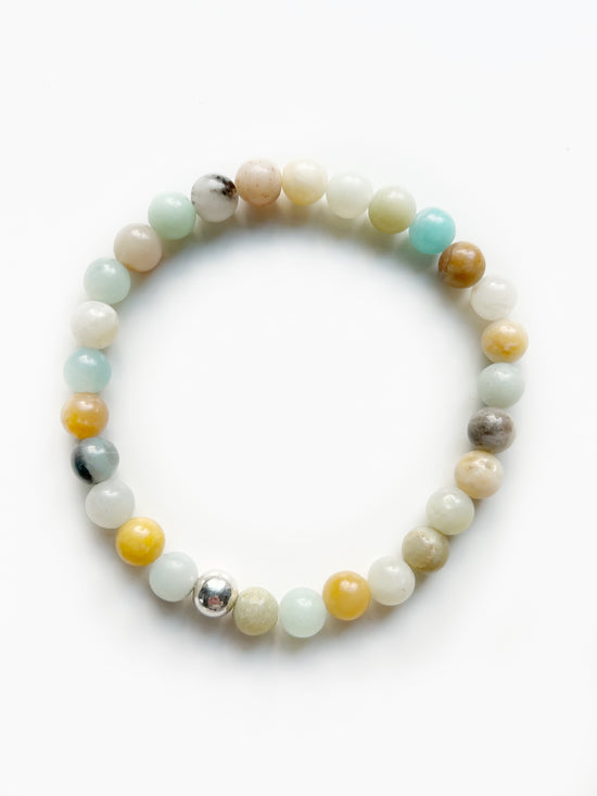 a multi colored stretch bracelet with light blue, yellow, black, white and orange beads. And one silver bead