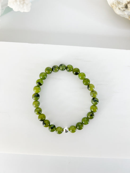 Canadian Jade stretch bracelet. darkish green beads with black flecks in them. The bracelet has one silver bead.