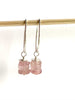 video of strawberry quartz earrings dangling from a small dowel